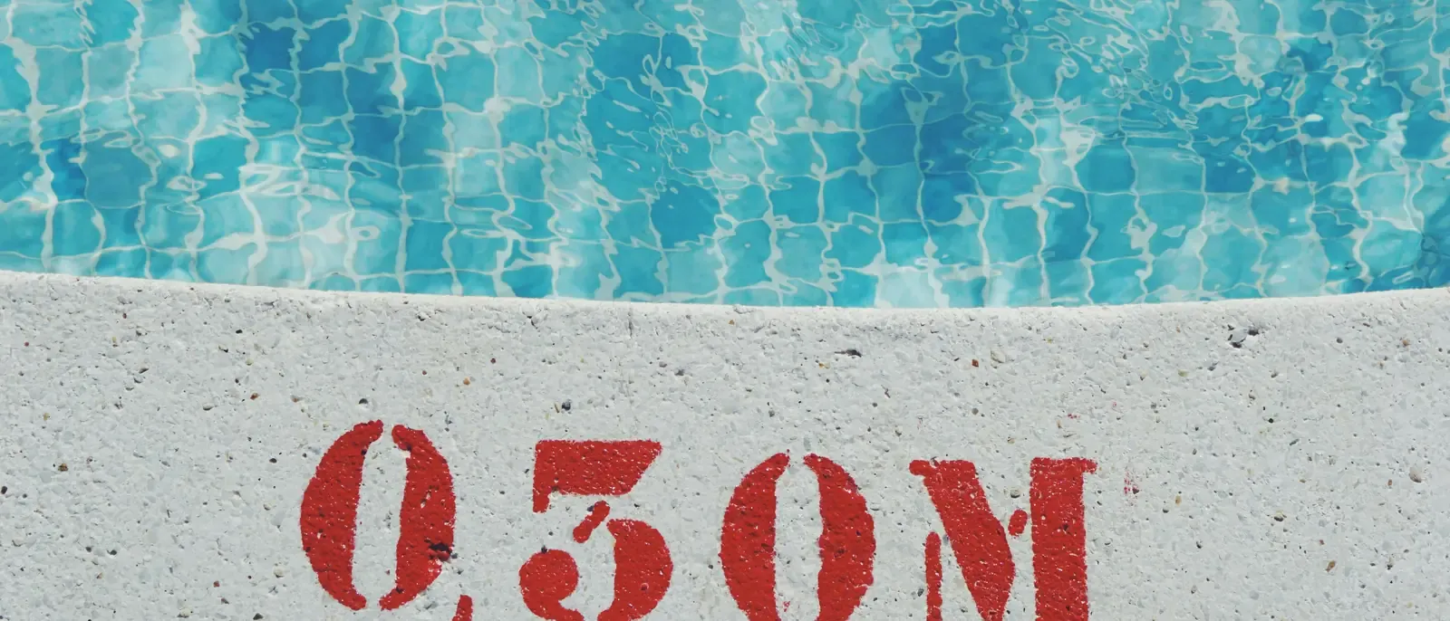 A depth marker stencilled in red on a pale pool edge reads "0,30 M", with tiled water above it